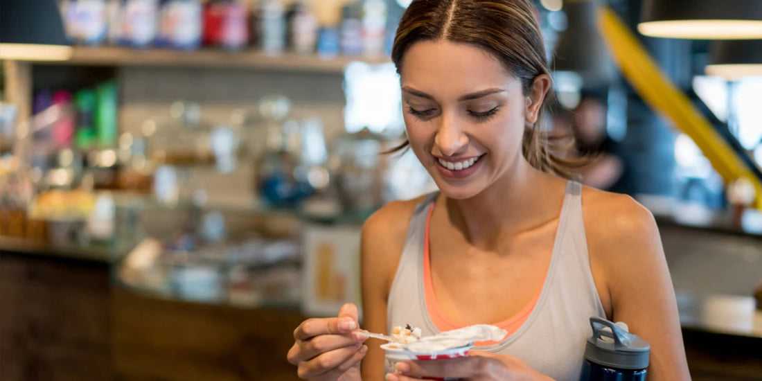 a woman holding a small plate of food inside a well-lit café