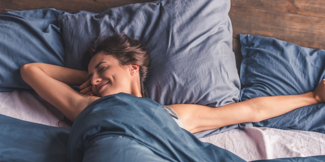a woman smiling while stretching in bed