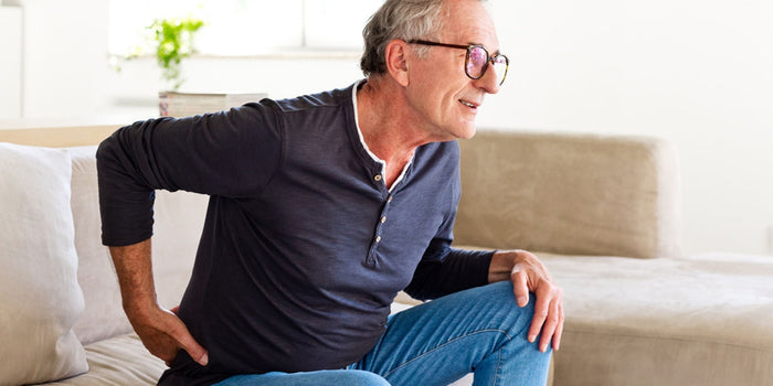 a mature man beding over and holding his lower back in pain