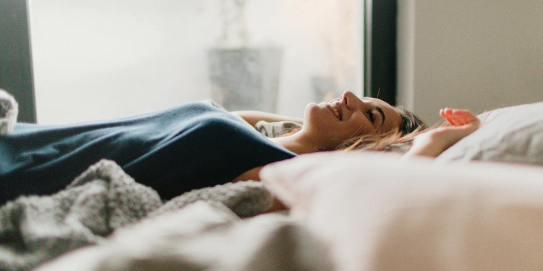 a person laying on a bed surrounded by a blanket smiling
