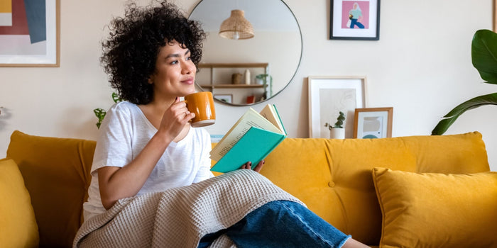 a woman sitting in the sun while drinking a coffee