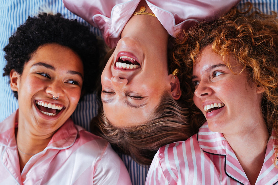 3 women wearing pink pyjamas laughing with eachother