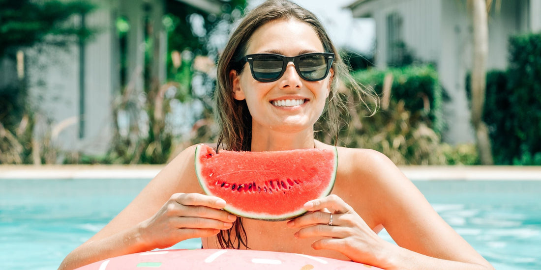 a person in a pool holding a watermelon slice