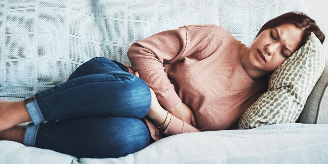 Woman with stomachache laying on lounge on her side in pain