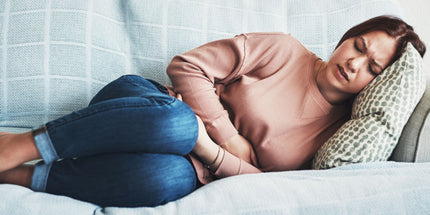 Woman with stomachache laying on lounge on her side in pain