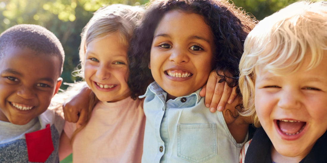 A group of kids with their arms around each others shoulders smiling and laughing