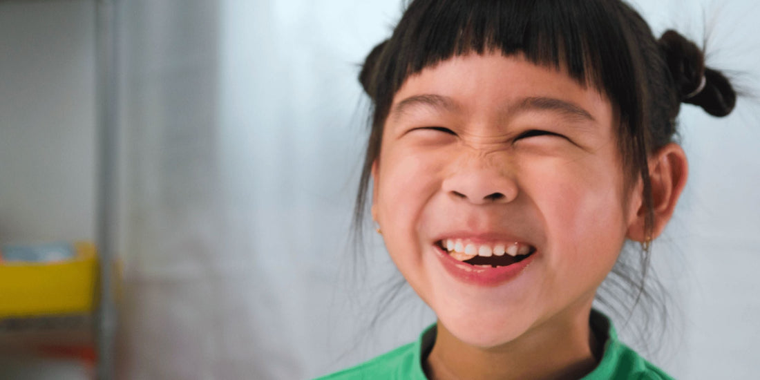 Little girl smiling broadly while chewing on a gummy