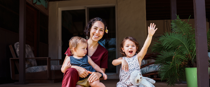A smiling mum with her two children on their patio steps