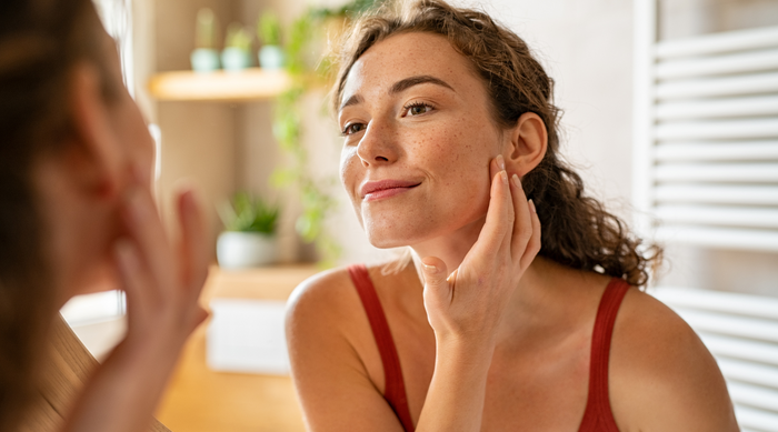 Woman observing her skin in the mirror for signs of skin dermatitis