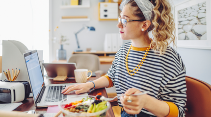 Woman working on her laptop eating a prebiotic-rich salad