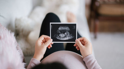 Pregnant woman holding ultrasound scan of baby