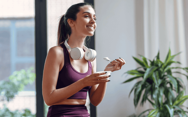 Woman in active wear enjoying a prebiotic and probiotic yoghurt