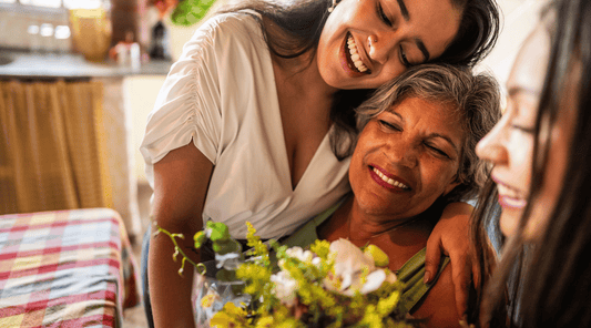 Older adult smiling gently while surrounded by supportive family.
