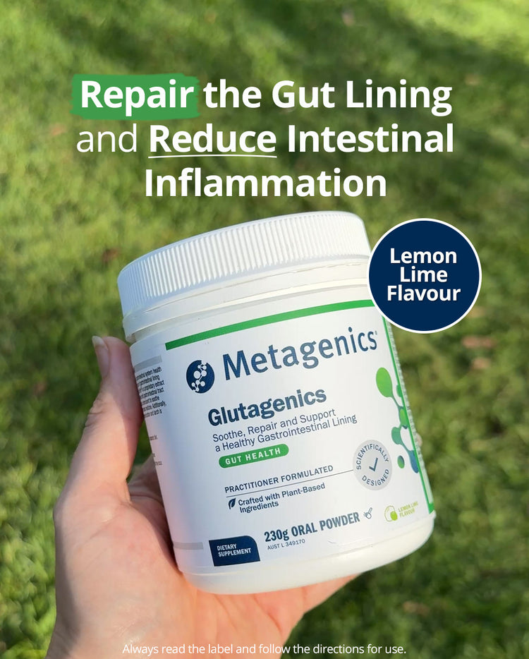 Hand holding a Metagenics Glutagenics 230g Lemon Lime flavour gut‑health supplement container outdoors, with text highlighting benefits: repair the gut lining and reduce intestinal inflammation.